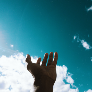 person s hand reaching for the sky