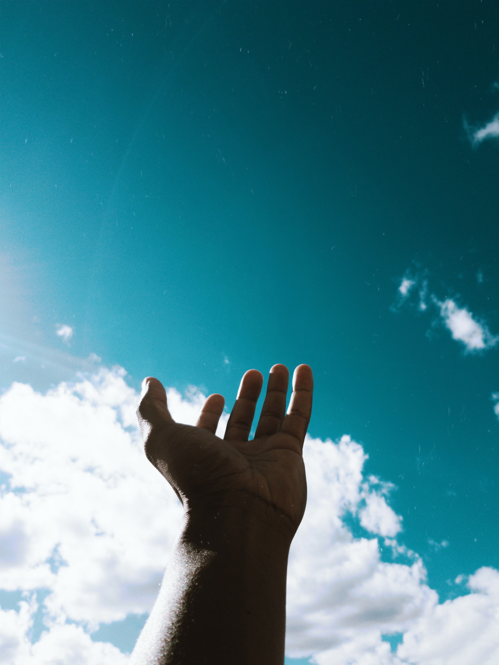 person s hand reaching for the sky