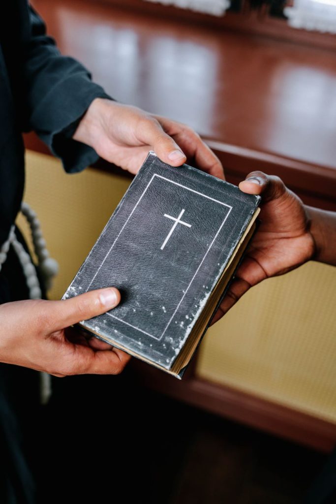 a priest handing a bible to a person